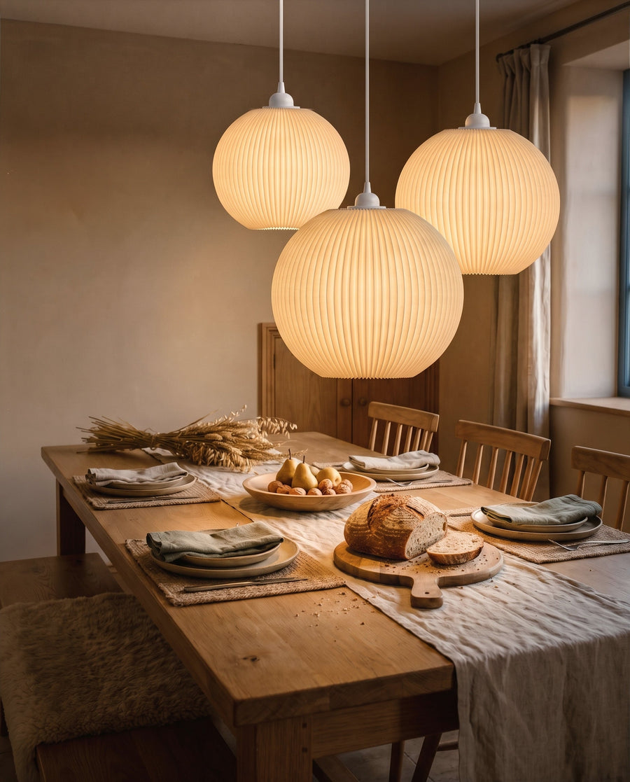 Drei Riga Plissee-Lampenschirme Kugel in Beige, Größen M, L und XL, leuchten als Traube über dem gedeckten Esstisch